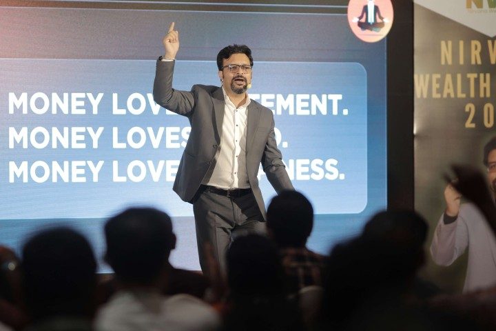 Pradeep Rawal speaking on stage at a Nirvana Wealth Retreat session